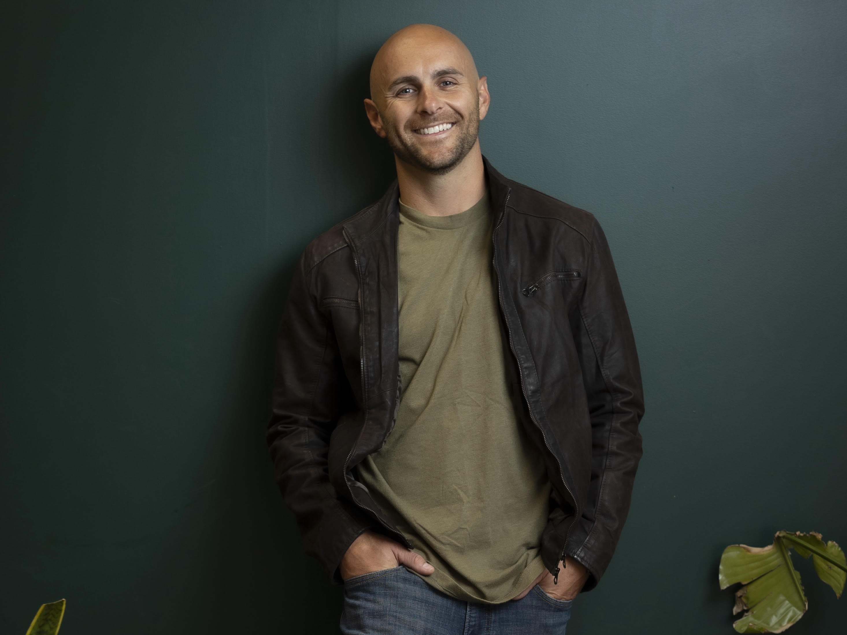 Portrait of Cam McGrew, smiling against a deep green wall