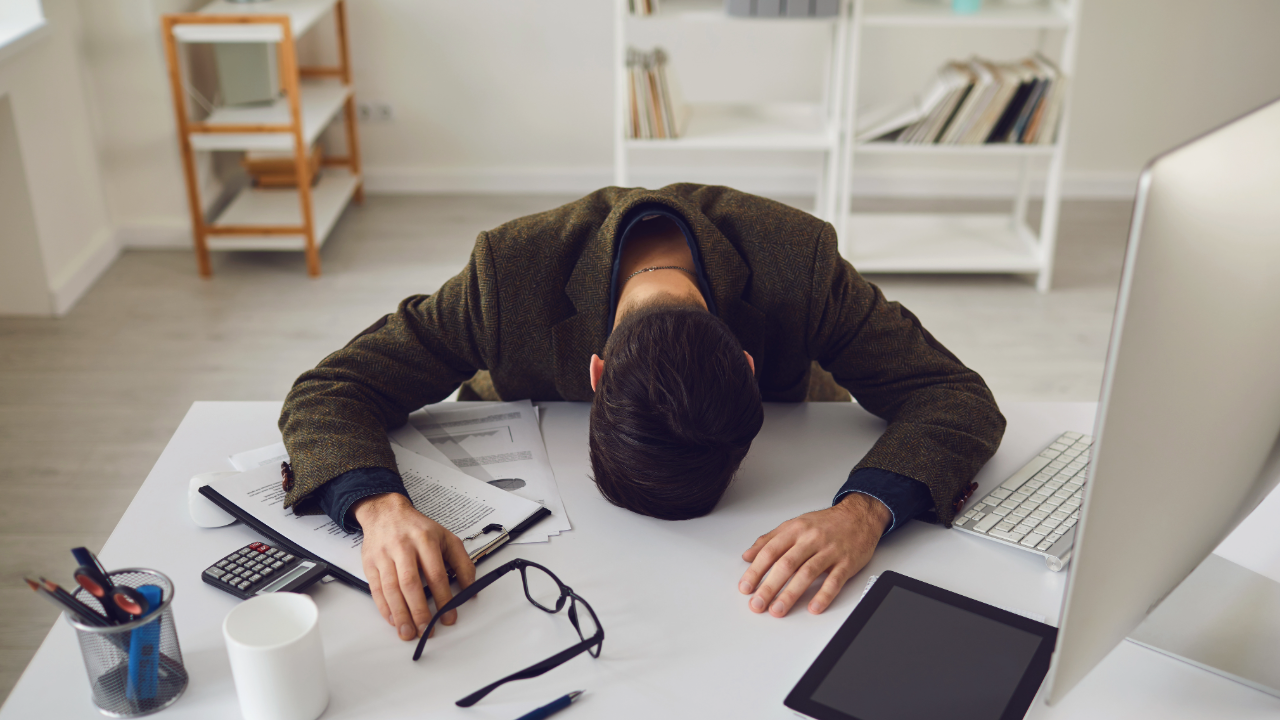 AI workload creep causes stressed out employee head down on desk overwhelmed