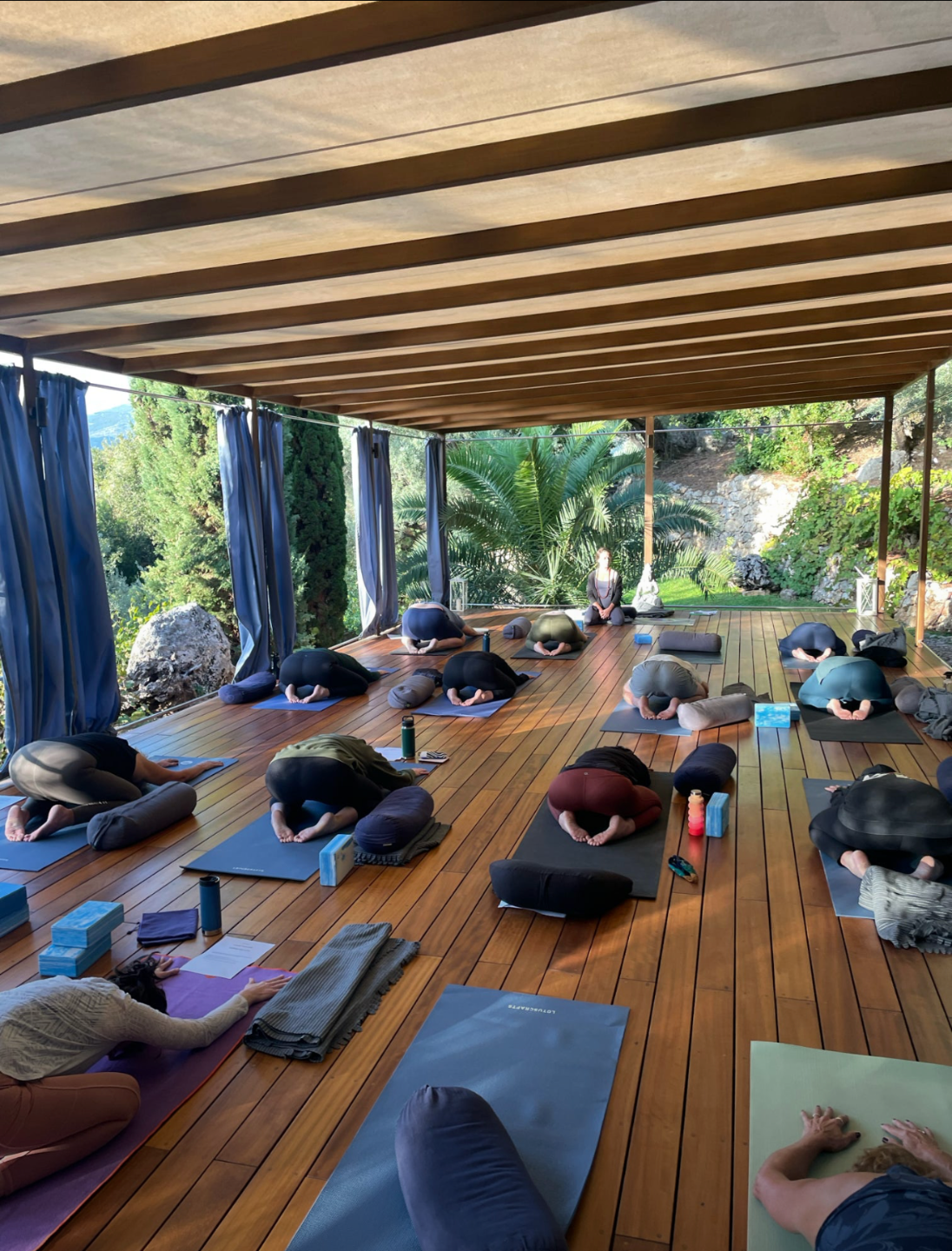 Women practicing yoga together on an open-air wooden terrace