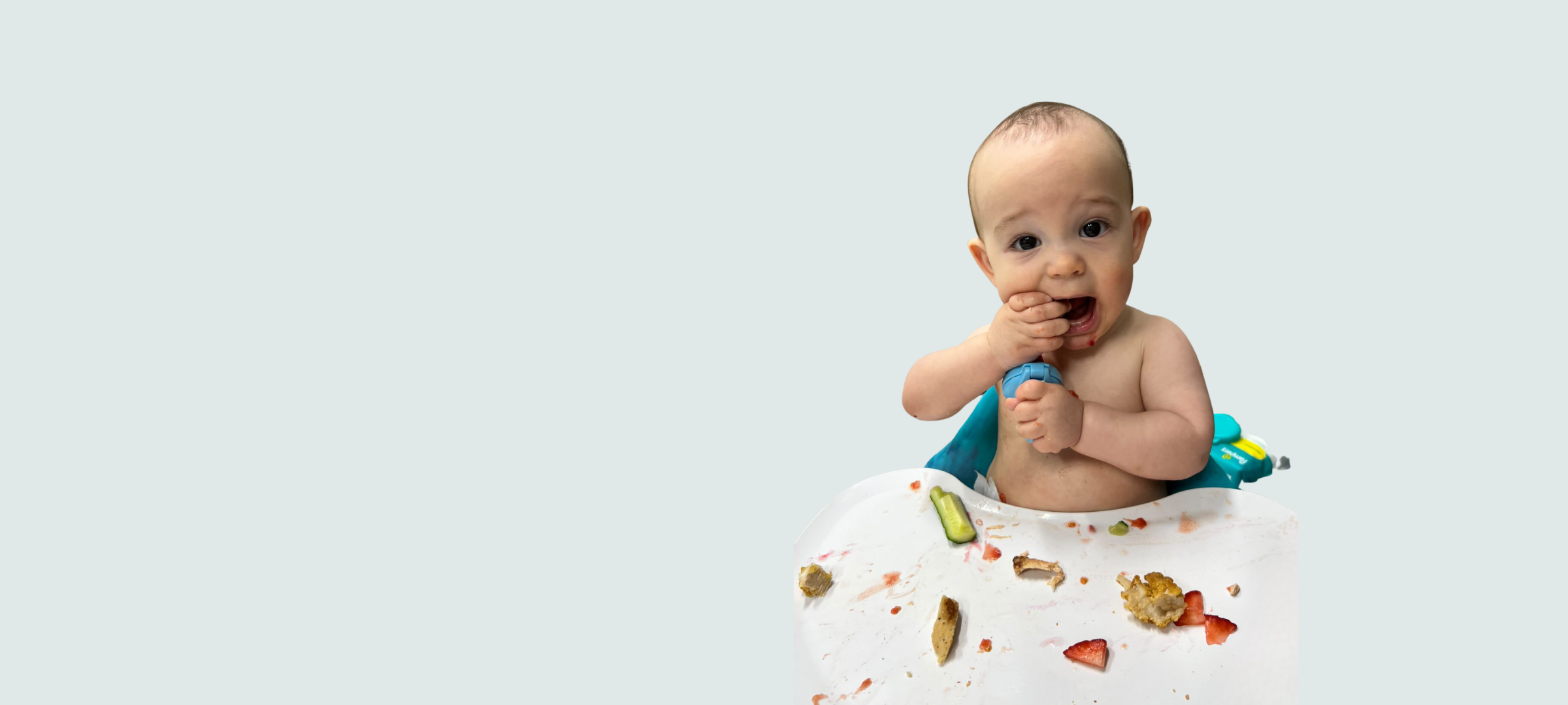 Baby in a high chair tasting first foods