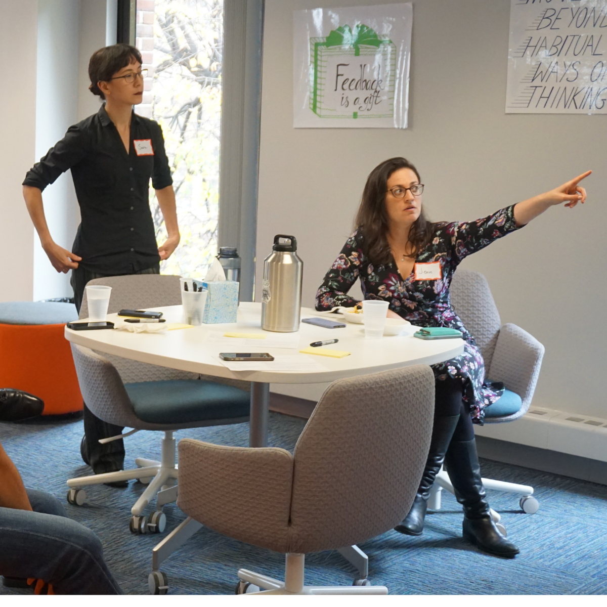 Jenn Felsted-Knight in a workshop with healthcare professionals, pointing toward ideas on the board with other participants listening