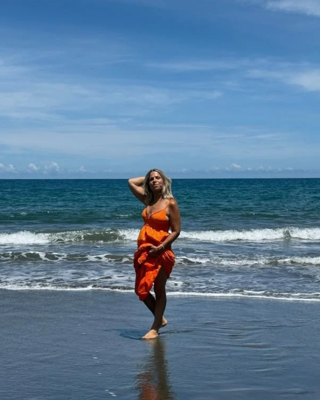 Karen Schachter walking the beach in an orange dress