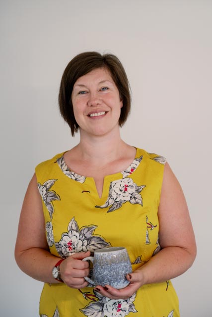 Beshlie Donaldson in a yellow floral top, smiling and holding a mug