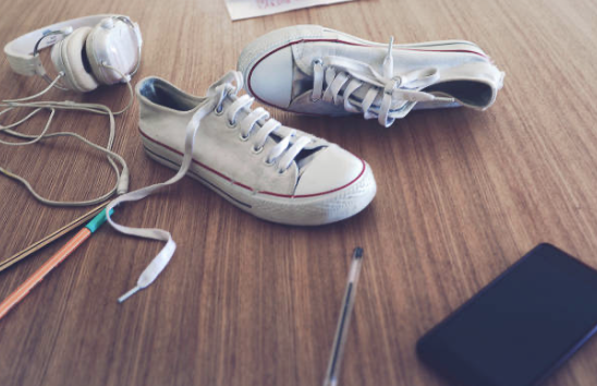 Sneakers, een koptelefoon en een telefoon op een bureau