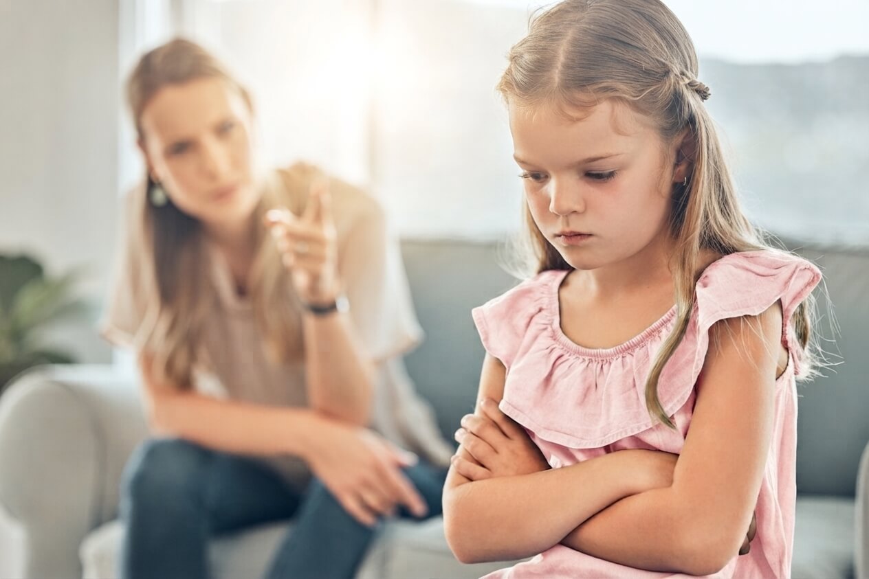 Moeder in gesprek met haar dochter, die haar armen over elkaar heeft