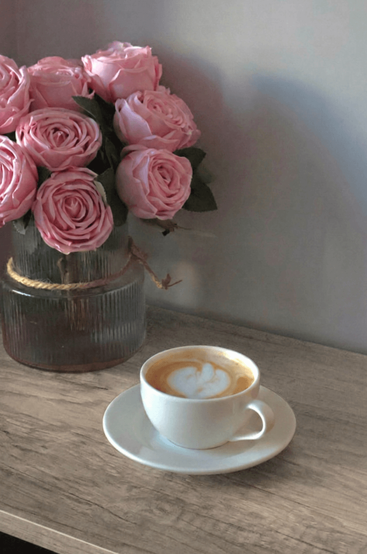 Roze rozen en een kop koffie op tafel