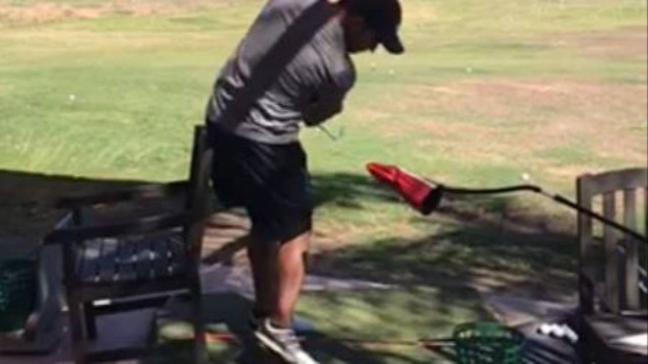 Golfer swinging through impact at the driving range