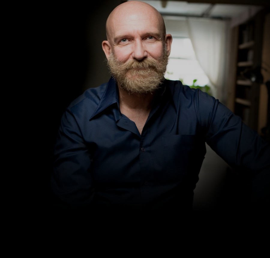 John Dapolito smiling in a dark room, wearing a navy shirt