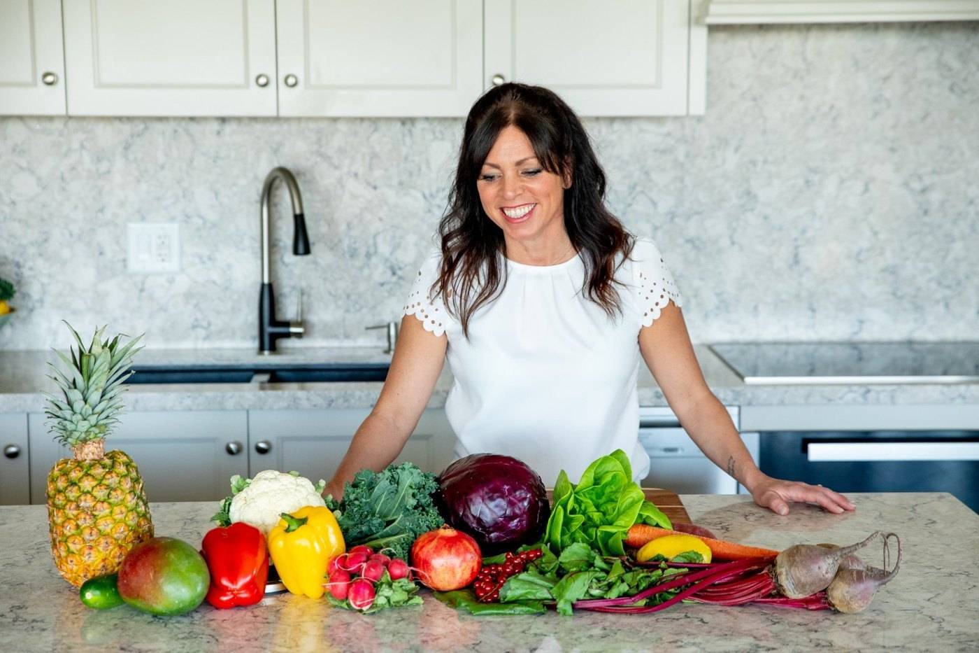 Amy at her kitchen counter behind a spread of colourful vegetables