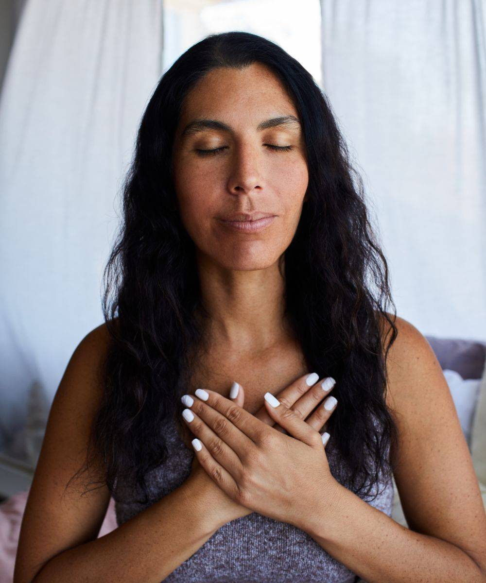 Woman with eyes closed and hands on chest
