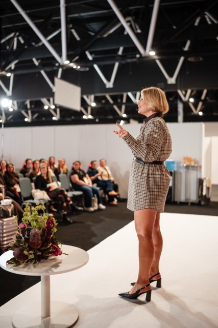 Tamara Reid speaking on stage at an industry expo
