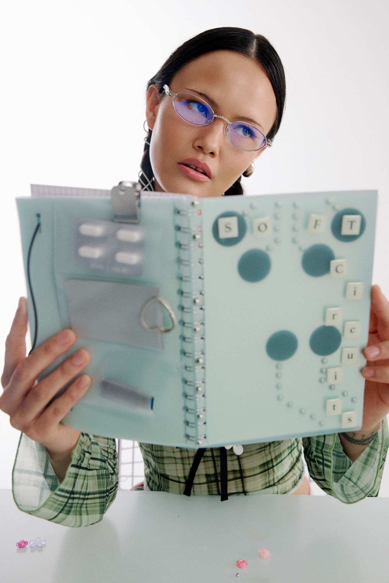 An educator in purple glasses reading a design folio