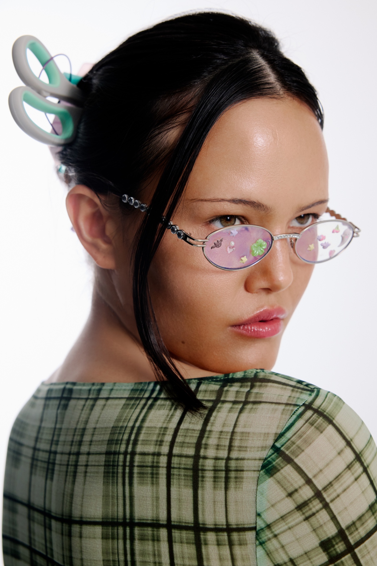 A hair and beauty industry educator in pink glasses looking over her shoulder