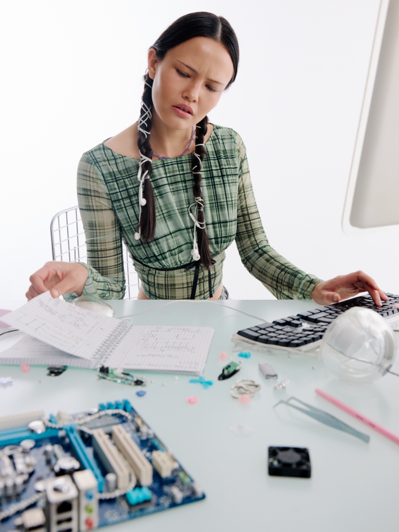 An educator frowning at paperwork beside an open computer