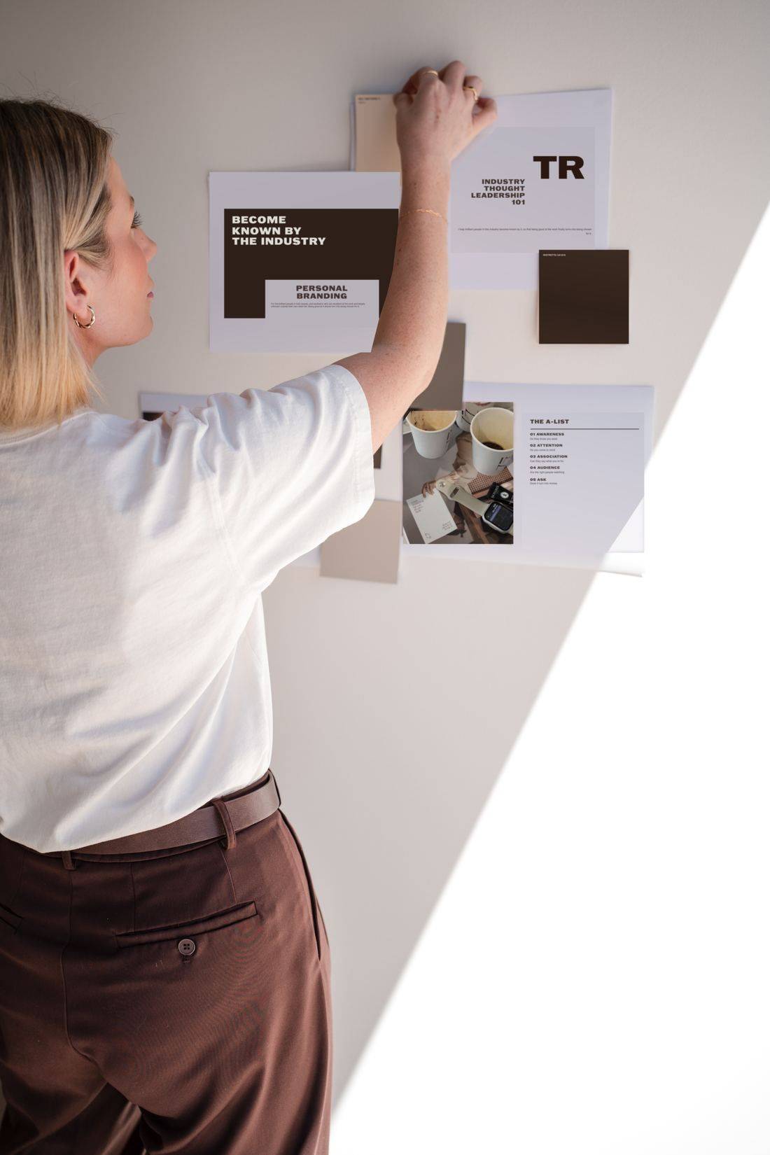 Tamara pinning a personal branding moodboard to the wall
