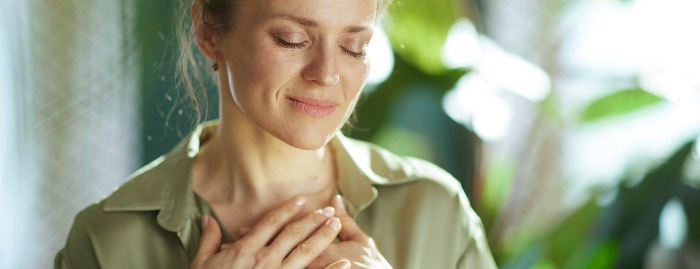A woman with her hands on her heart, eyes closed