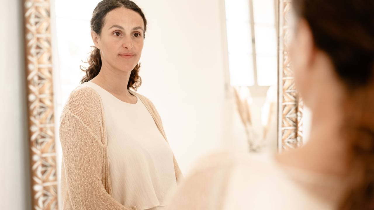 A woman calmly looking at herself in a mirror
