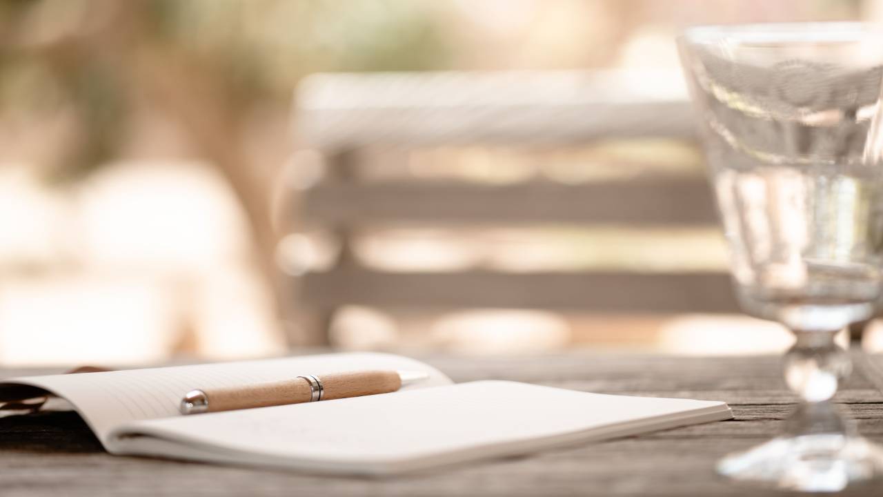 An open notebook and a pen on a wooden table