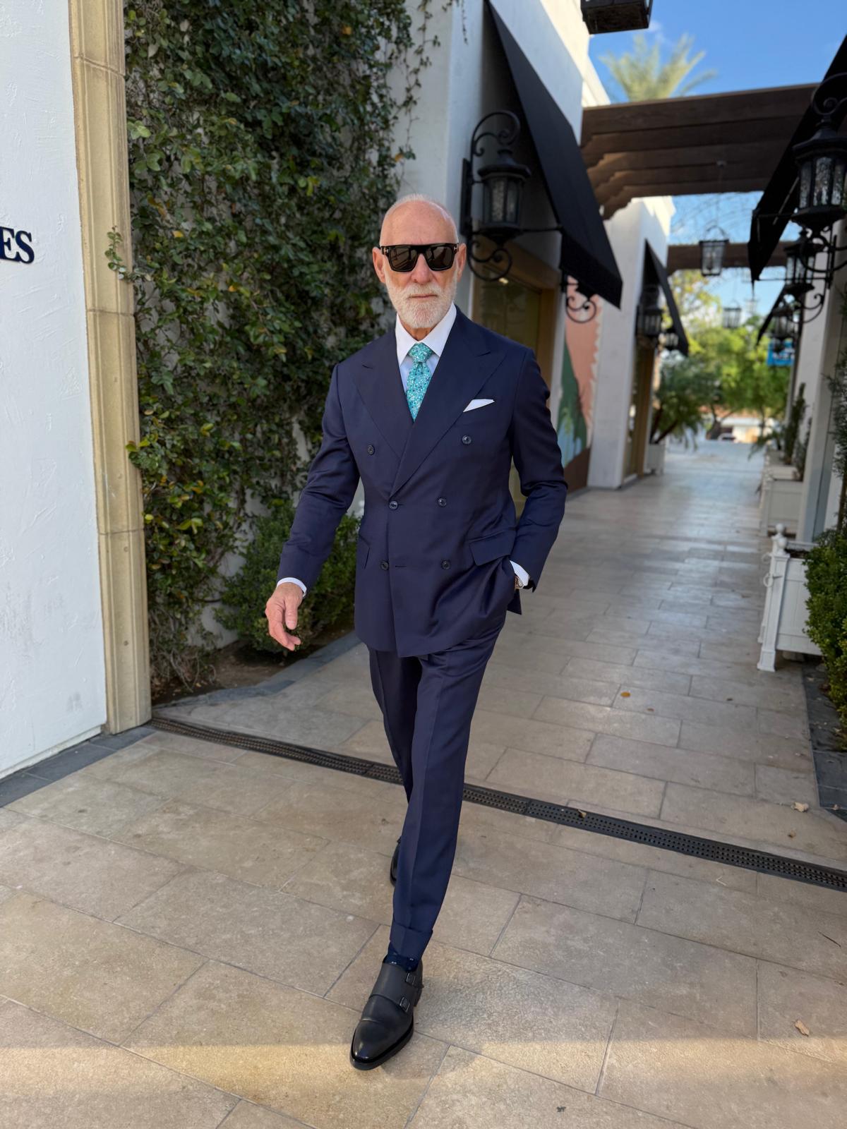 Randy Willard walking in a navy double-breasted suit and teal tie