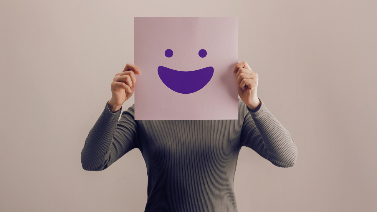 Woman holding up smiley face sign over her face