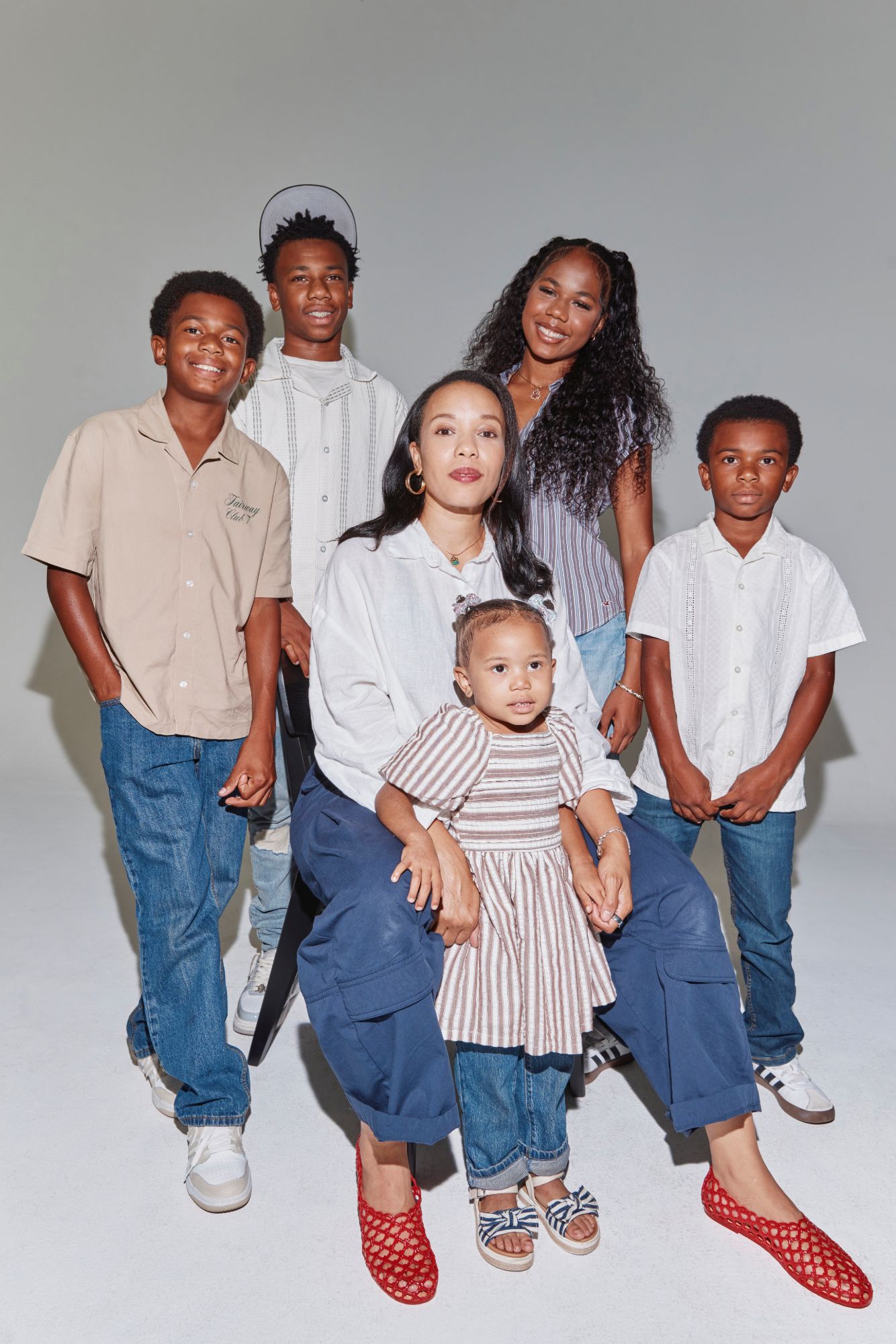 The founder seated in a studio with a toddler on her lap, surrounded by four older children