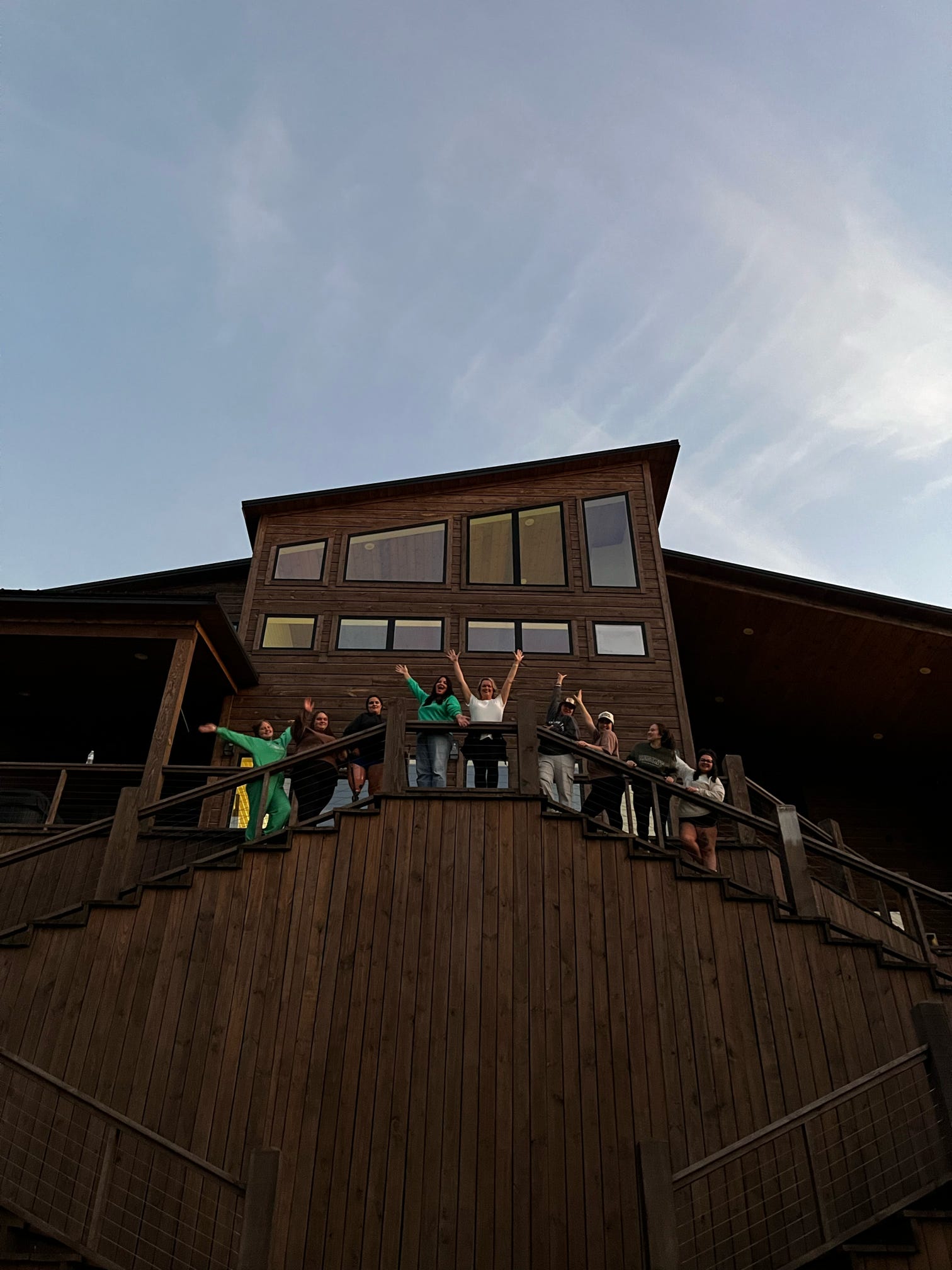 A group of women waving from the deck of a retreat cabin