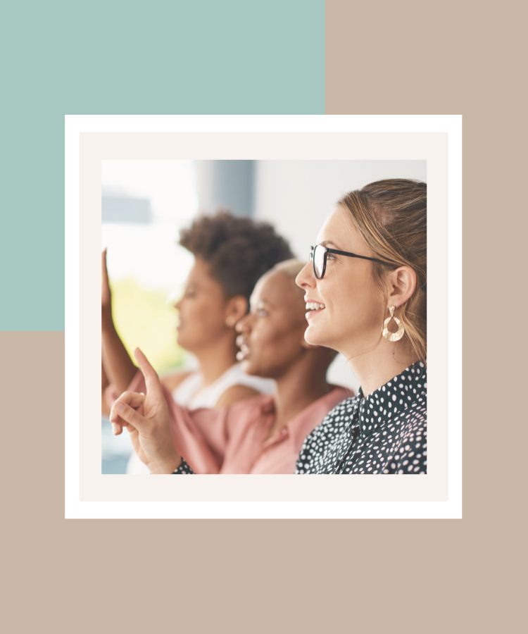 Three women participating in a group discussion, with one smiling and raising her finger, presented in a white photo frame against a soft sage green and beige background.