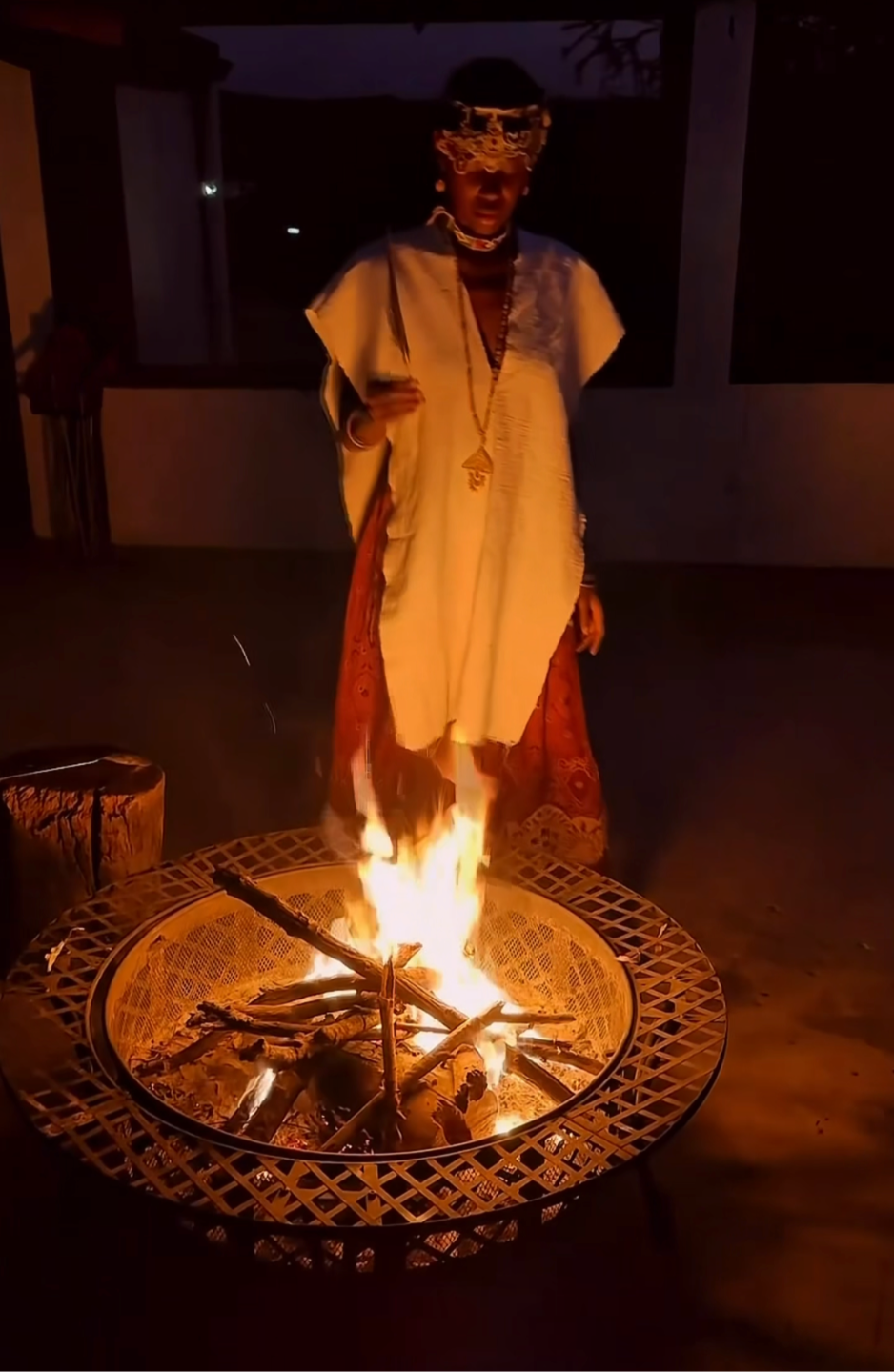 Gogo Thule in white, standing by a ceremonial fire