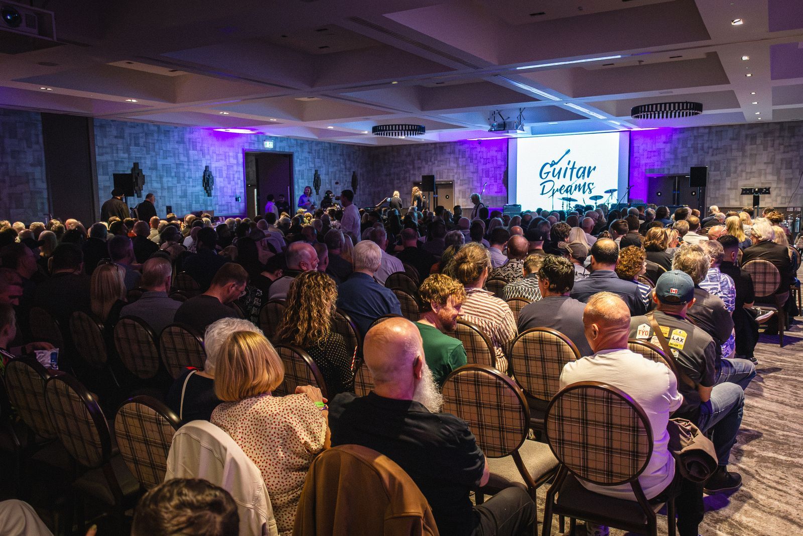 A packed room facing the Guitar Dreams screen at the grand finale