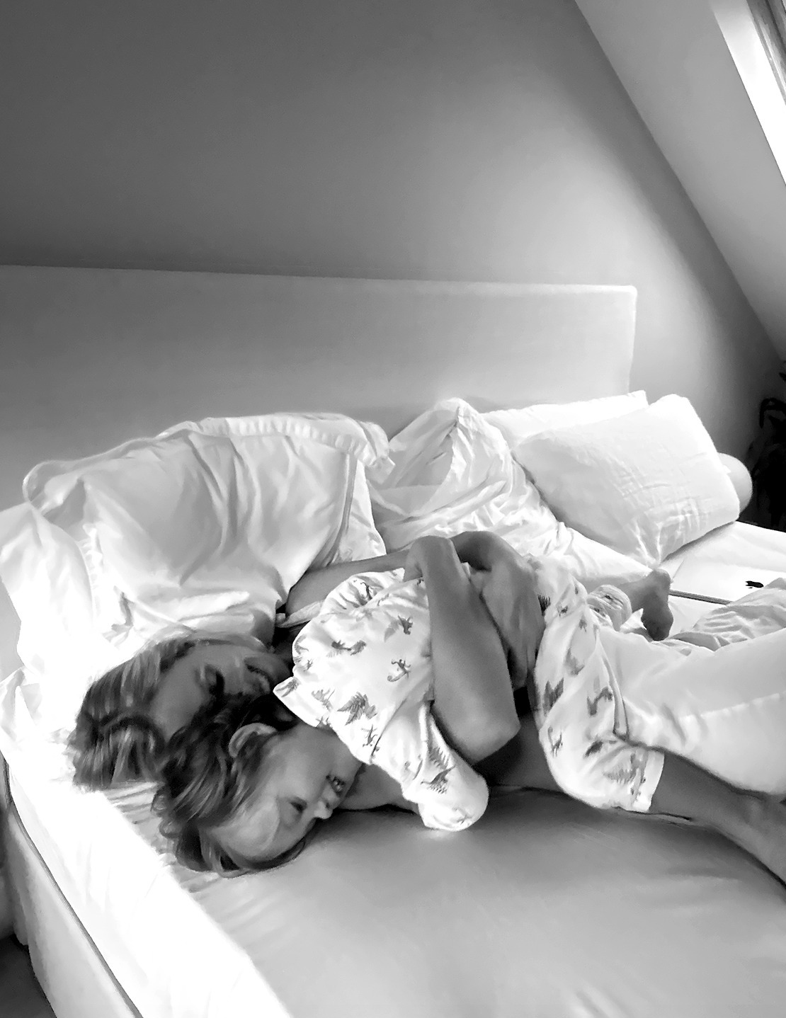 A mamma hugging her little one in bed