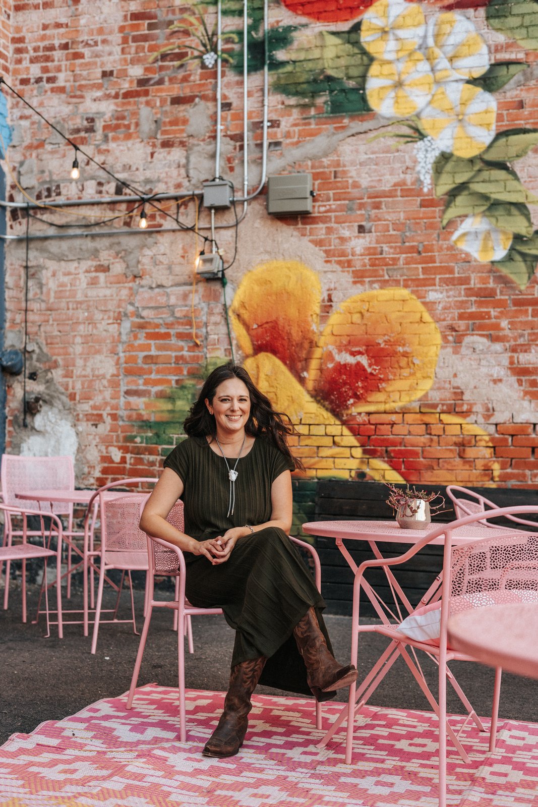 Michele Larson, Cheyenne Realtor, smiling in front of a colorful flower mural
