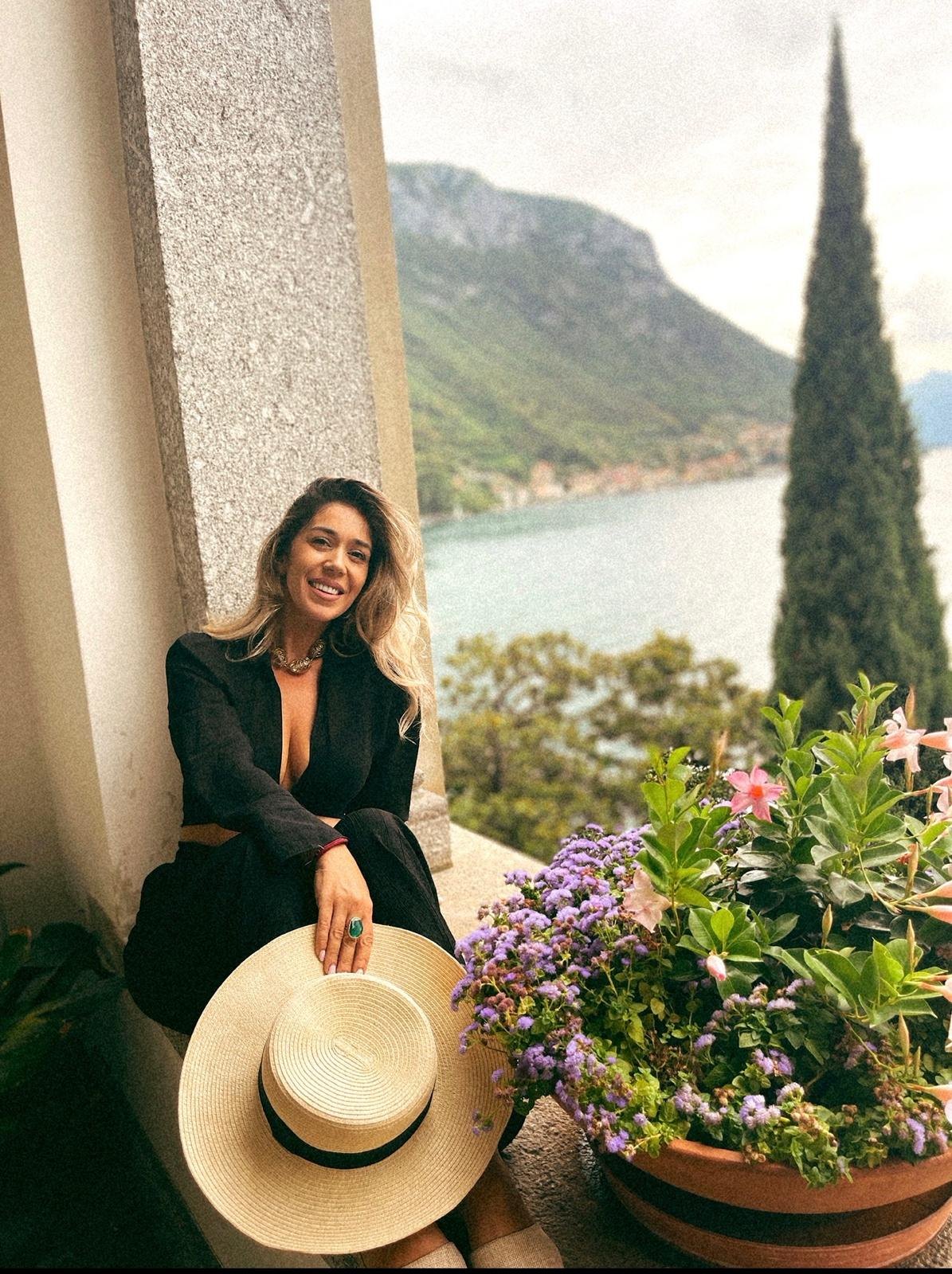 Flavia pe o terasă, cu pălăria în mână