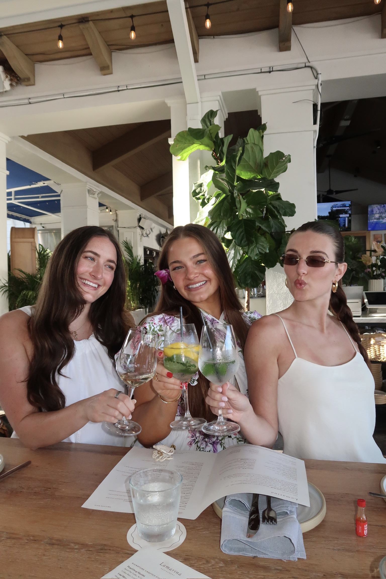 Three women from The Creator Current cheering with drinks at a restaurant table