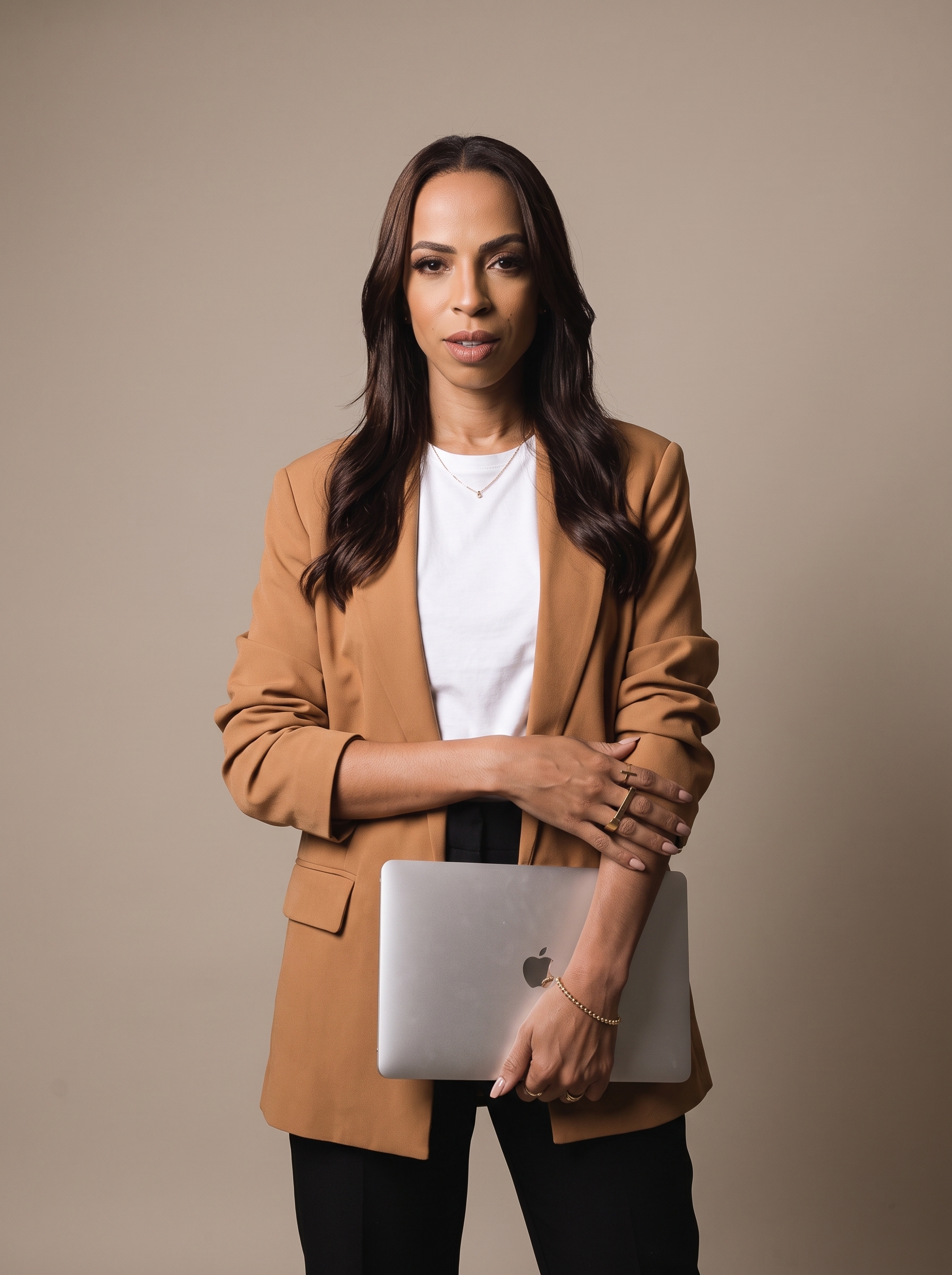 Marcela de blazer caramelo com o MacBook
