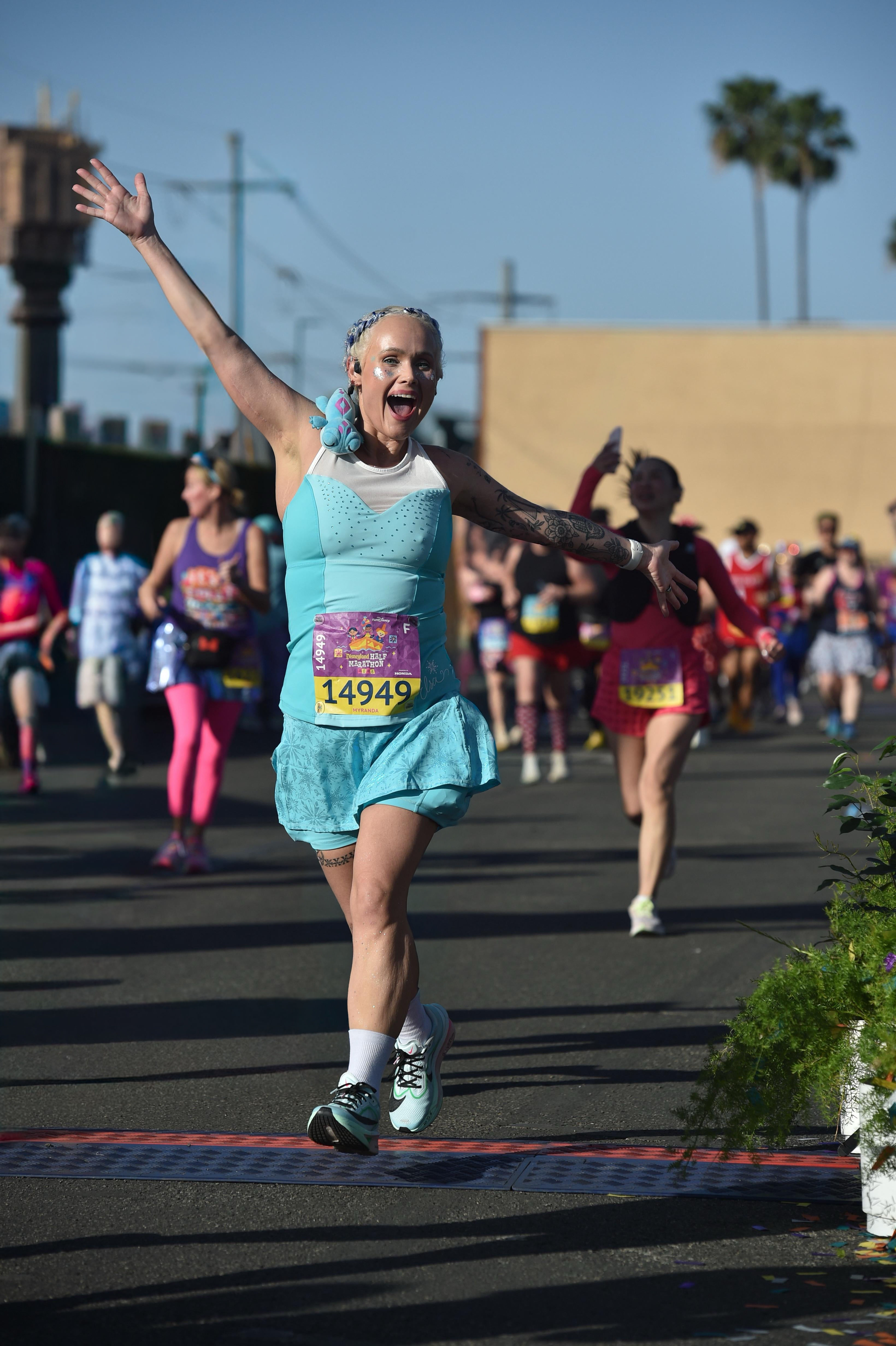 Myranda running in a race, wearing a light blue running dress and her race bib