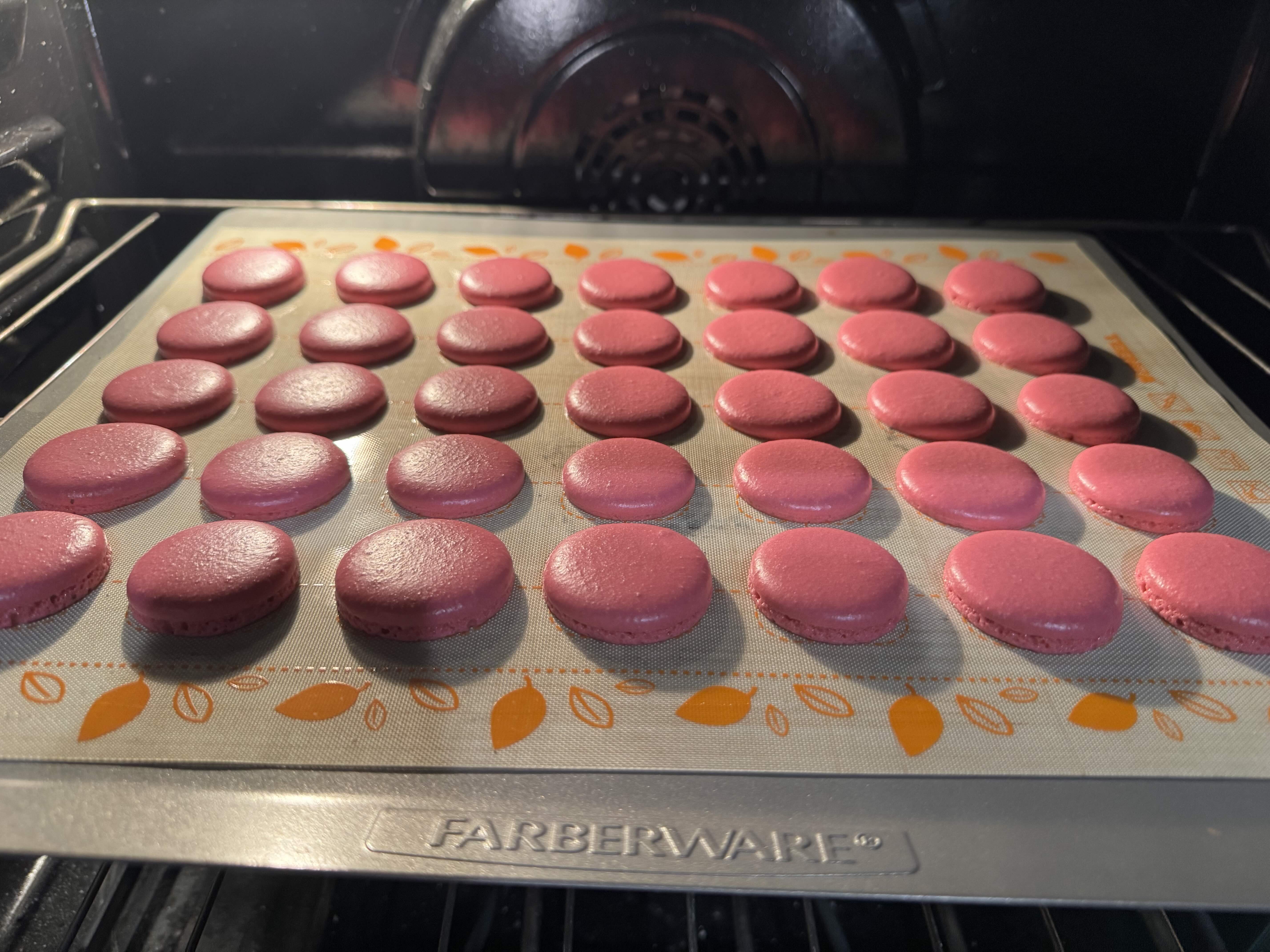 A tray of pink macarons baking for a charity bake sale