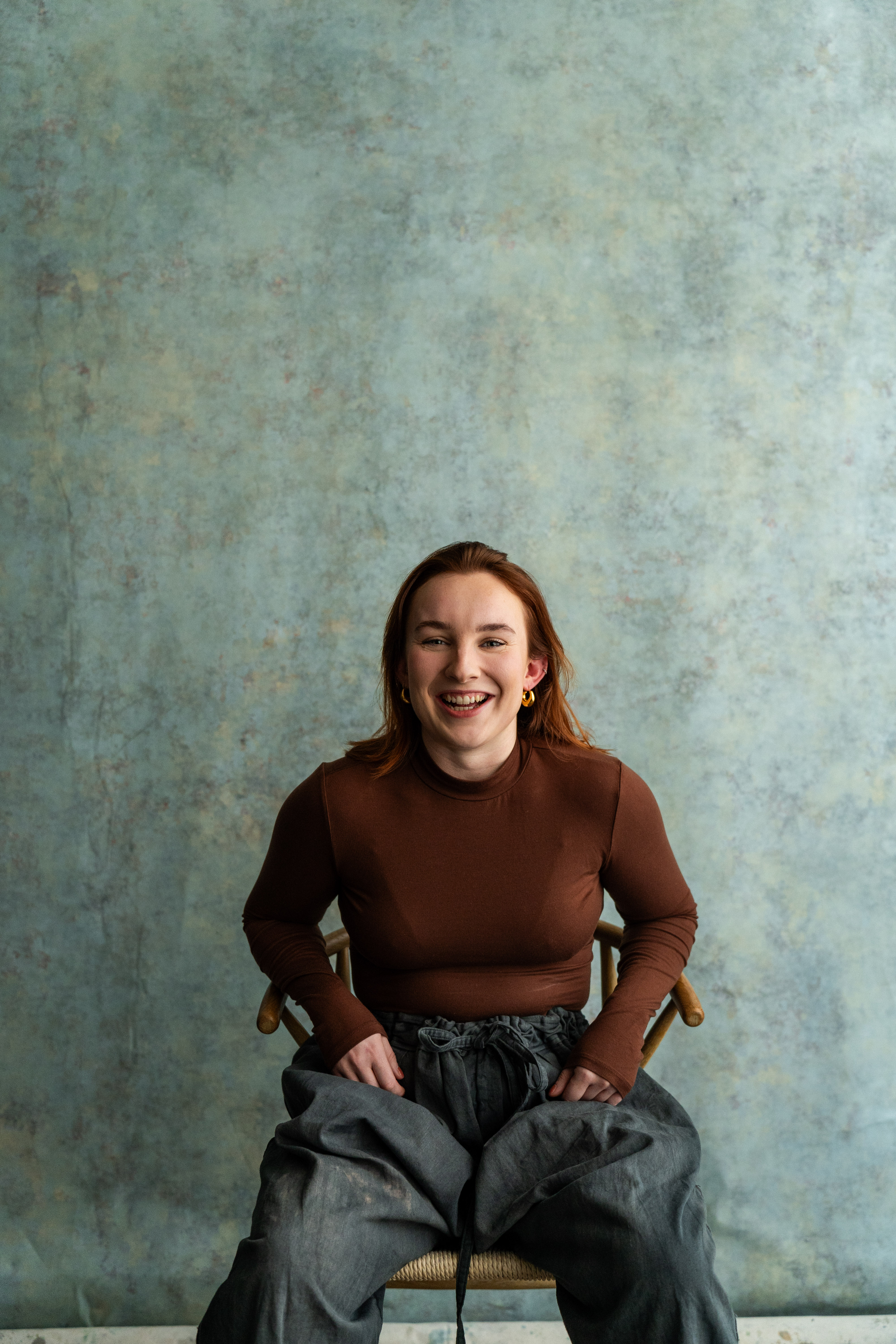 Molly Parker, voice coach and director of The Practice Rooms, laughing on a chair