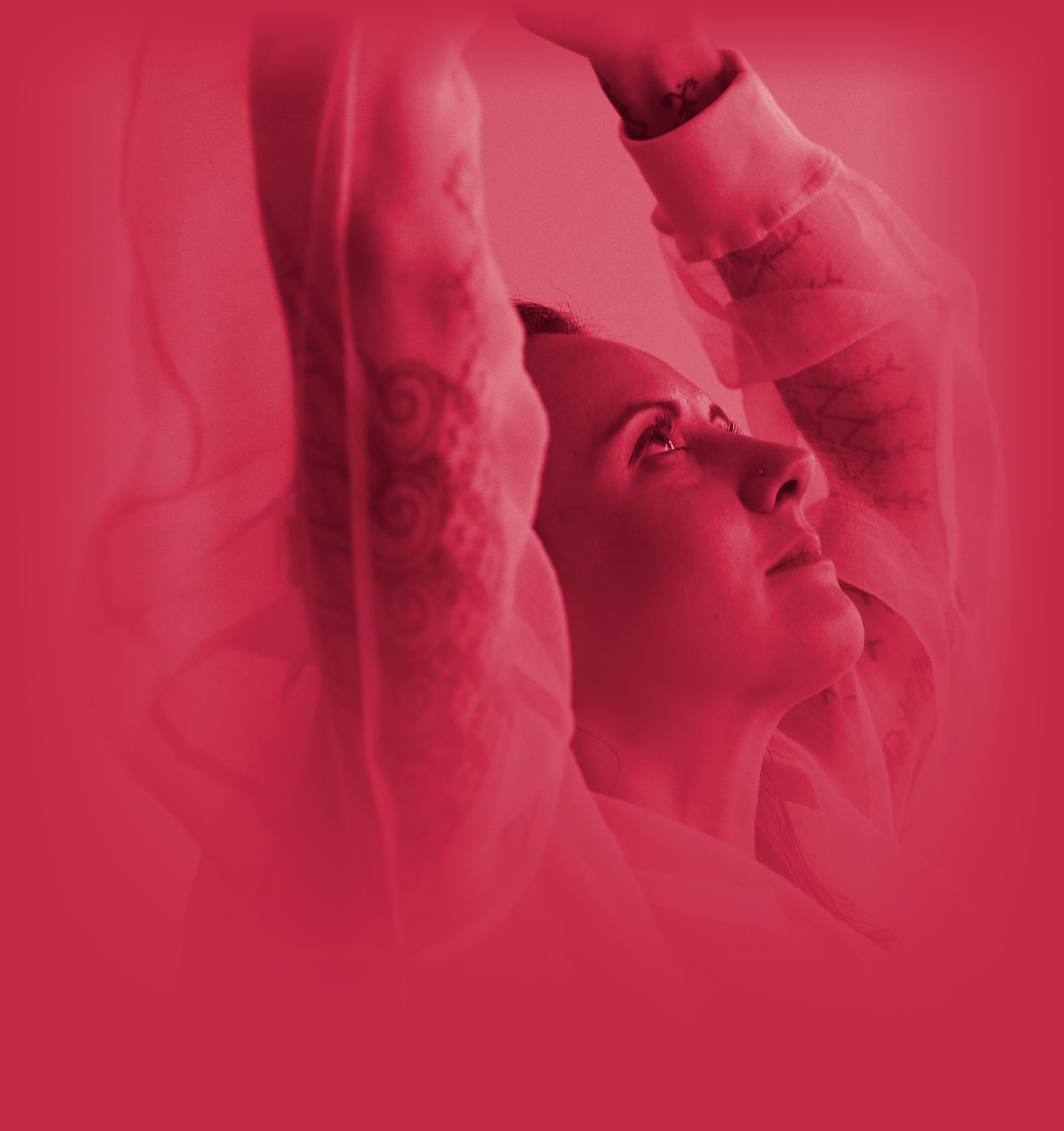 Alexia with arms raised, looking up, in red