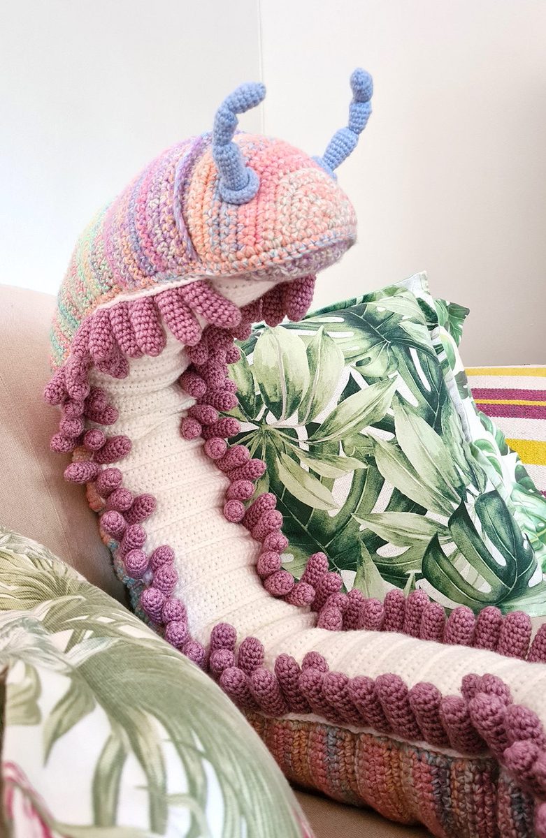 A very long crocheted snake coiled across a sofa
