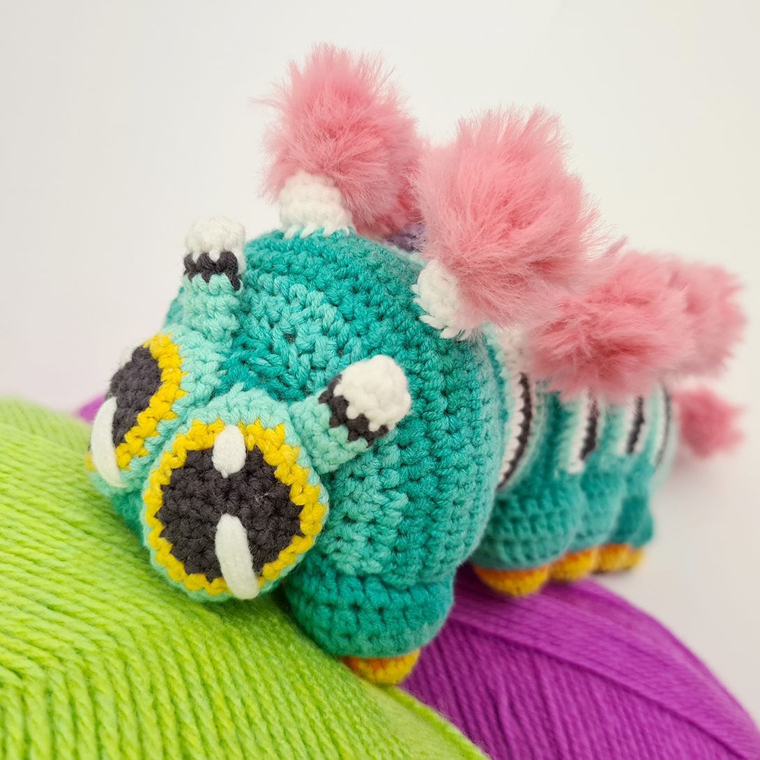 A teal crocheted caterpillar built from repeated segments