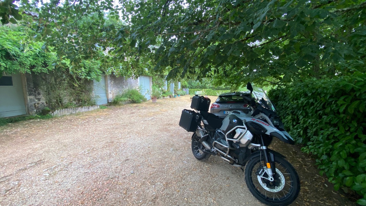 Motorcycle parked beneath trees during a ride through France