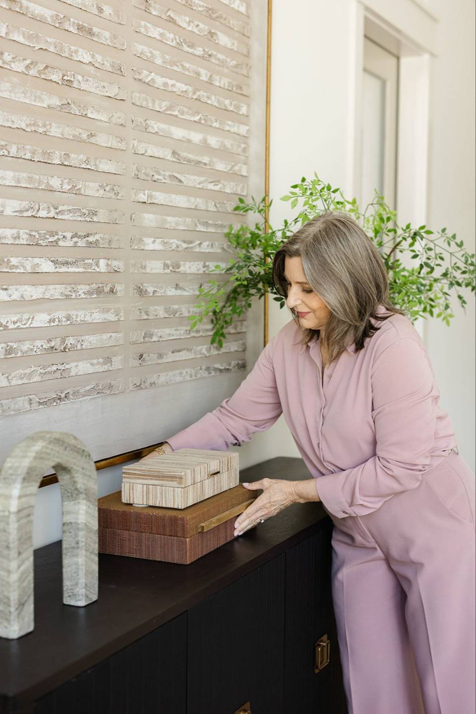 Home staging professional arranging decorative accessories on a console table to create a balanced interior design.