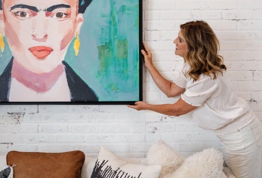 staging studio co-founder julie young hangs a large piece of artwork