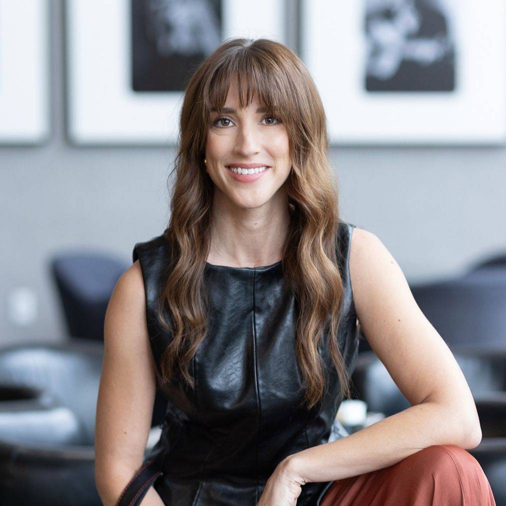 Vanessa Joy, wedding photography business coach, smiling, seated on a couch