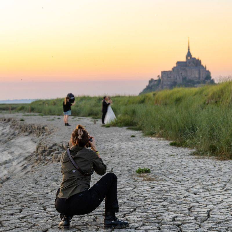 Vanessa Joy photographing a bride and groom at Mont Saint-Michel during golden hour