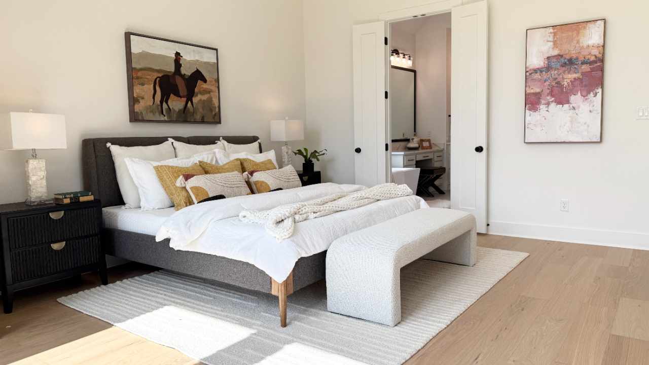 Modern bedroom with a gray upholstered bed, yellow accent pillows, and light wood floors.