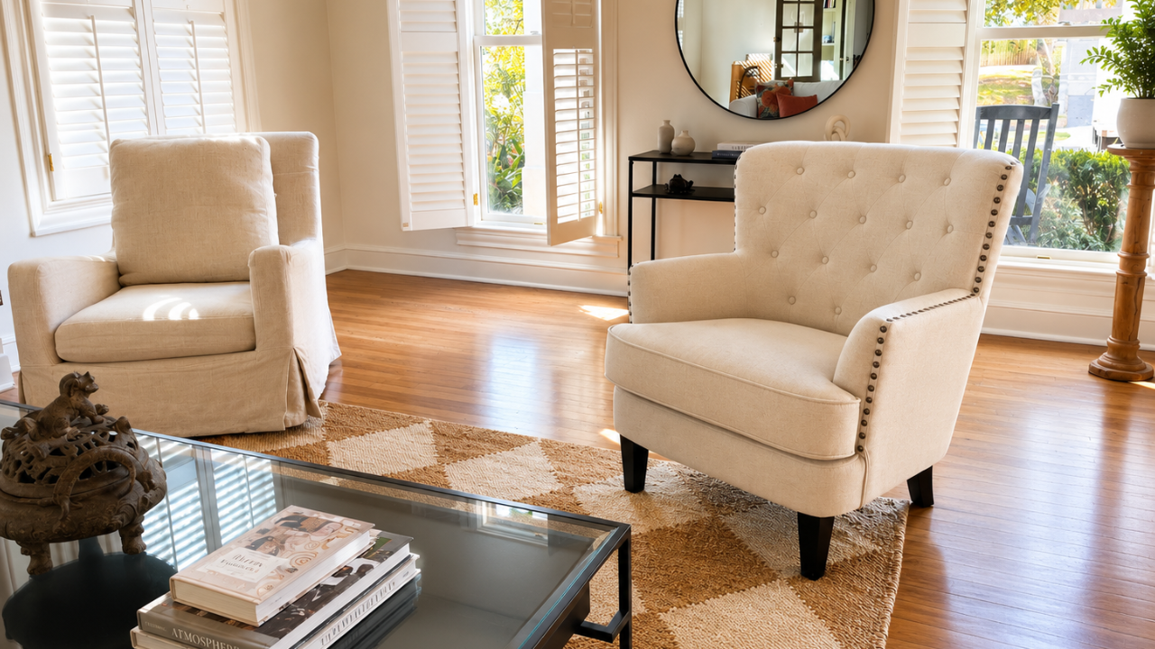 Modern living room staged with neutral armchairs, natural light, and hardwood floors.