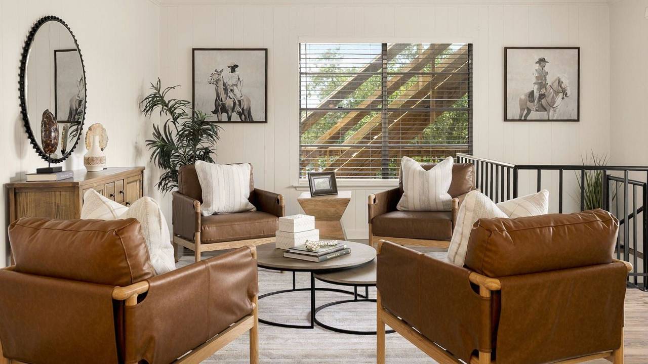 Sitting area with leather armchairs, round coffee tables, and equestrian artwork.