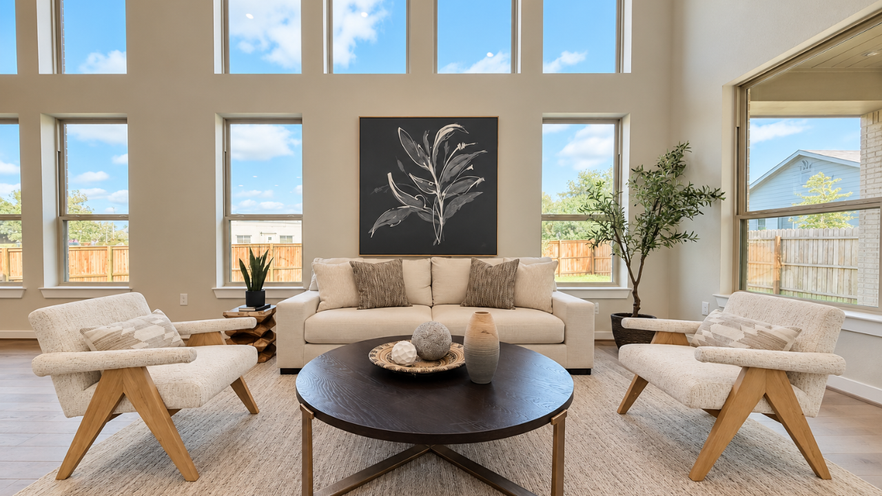 Bright living room with a cream sofa, armchairs, and tall windows.