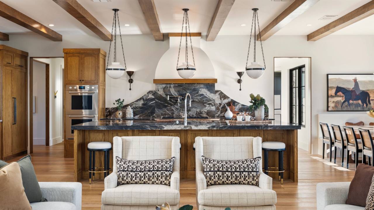 Open kitchen with wood cabinetry, marble countertops, and exposed ceiling beams.